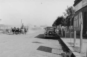 Dorfstraße : Blick auf eine staubige Dorfstraße mit Pferdefuhrwerken