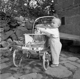 Kleinkind, an einem Kindersportwagen stehend