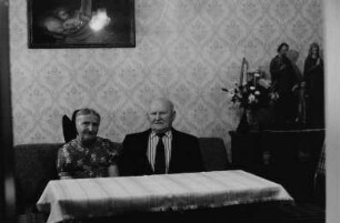 Großeltern der Familie W. im Wohnzimmer. Großmutter mit Haube (sorbische Tracht), im Hintergrund die "Heilige Familie" als Plastik