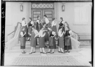 Haushaltungsschule in Gammertingen 1931; Junge Frauen mit Schürzen bei einer Aufführung mit Geigenspielerin auf einer Treppe vor dem Hauseingang