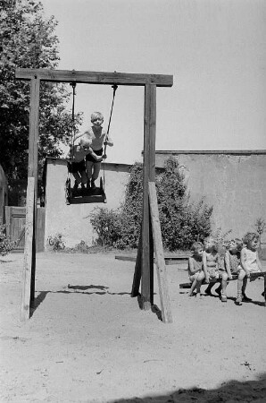 Betriebskindergarten der VEB Stralauer Glaswerke : Kinder auf einem Spielplatz auf einer Schaukel