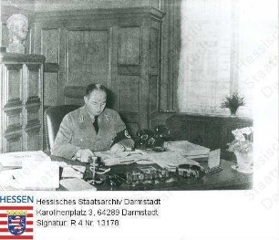 Schmidt, Wilhelm Georg (* 1900) / Porträt in NS-Uniform am Schreibtisch in seinem Arbeitszimmer im Haus des Deutschen Handwerks in Frankfurt am Main sitzend, Brustbild