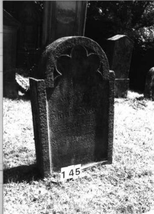 Grabstein 145 (Index: 100085459) Maße HxBxT: 90x60x13 cm Beschreibung: Stele, eingezog. Rundbogenabschl. , Schriftfeld eingetieft mit Maßwerk auf Vordersei: Grabstein 145