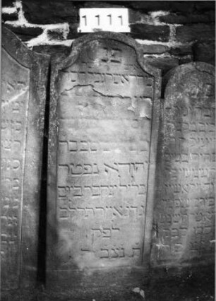 Grabstein 1111 (Index: 99630614) Material: Sandstein Zustand: stark abgeblättert, Textverlust Maße HxBxT: 122x51x11 cm Beschreibung: Stele mit eingezogenem Segmentbogenabschluß, Schriftfeld eingetieft: Grabstein 1111