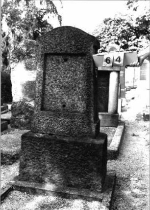 Grabstein 64 (Index: 99793105) Material: schwarzer polierter Granit Zustand: Schriftplatte fehlt Maße HxBxT: 140x52x24 cm Beschreibung: Stele mit überkragendem flachen Konvexbogenabschluß, Schriftfeld konisch, getreppter Sockel, Grabeinfassung: Grabstein 64