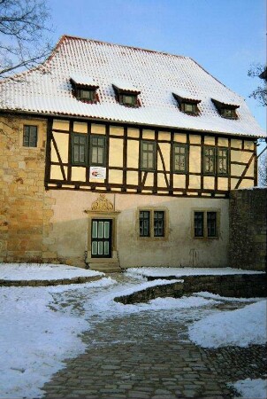 Burghof mit Natursteinpflasterung und gelbes Haus