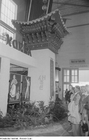 Besucher der Technischen Messe 1953 an einem Stand mit koreanischer Propaganda
