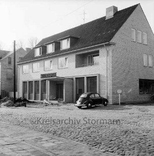 Kreissparkasse, Hauptzweigstelle: Paul-von-Schoenaich-Straße: Einweihung: Außenansicht: Strommast, Erdhaufen auf Fußgängerweg: parkender Pkw