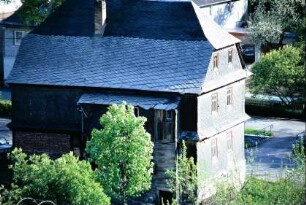 Rückseite eines hohen Schieferhauses mit Walmdach; Anbau von Außentoiletten