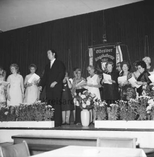 Oldesloer Singakademie von 1946: Oldesloer Hof: Saal: Festveranstaltung zum 25-jährigen Jubiläum: Chor und Chorleiter auf Bühne: hinten Fahne: vorn Blumenschmuck: 26.09.1971