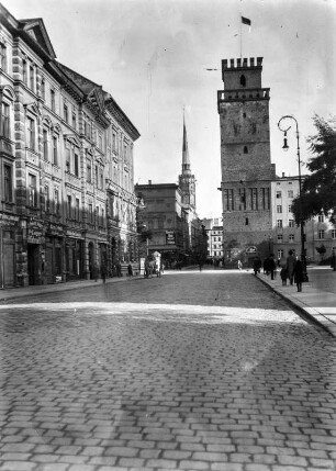 Münsterberger Turm : Der Münsterberger Turm, einer von zwei erhaltenen Türmen der mittelalterlichen Stadtmauer, links eine Häuserzeile mit Geschäften. In der Ferne ist der Ratsturm zu sehen.