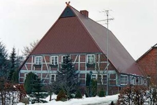 Am Schulzentrum 4: giebelständiges Fachwerkhaus: nach Neueindeckung: Straßenfront Wohntrakt, oben an Giebel Eulenloch, Giebelzier Pferdeköpfe: Traufseite, vorne Wohntrakt mit Eingangstür: Vorgarten, Weg, hinten rechts Gebäude [angeschnitten]