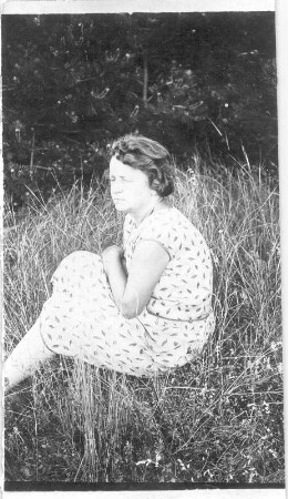 Etha Richter im Sommerkleid, auf einer Wiese sitzend