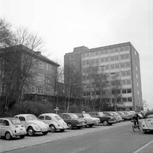 Erweiterungsbau "Hochhaus" vor Einweihung [später Gebäude B]: III. Bauabschnitt: links Hauptgebäude [später Gebäude A], dazwischen Verbindungstrakt: im Vordergrund Bangertstraße mit Parkplätzen für Pkw und Fahrradfahrer