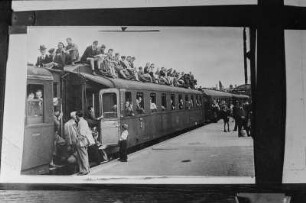 Bahnhofsszene in einem Berliner Vorort. Reproduktion : Mit Reisenden überbesetzter Personenzug in einem Vorort-Bahnhof von Berlin. Eingespanntes Positiv mit Ausschnittkennzeichnung