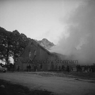 Gut Altfresenburg: Brand des Bullenstalls: Brandruine: Giebelfront: davor Feuerwehrleute und Helfer: hinten Rauchschwaden und Bäume: vorn Weg: 24. August 1971