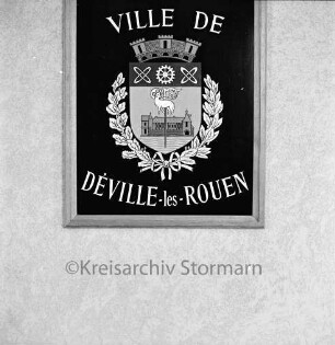 Schwesterstadt Déville-lès-Rouen: gerahmtes Stadtwappen an Wand