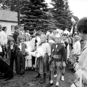 Kindervogelschießen: Festumzug: Schulkinder in Kostümen: hinten links Zuschauer: hinten Wohnhäuser und Bäume
