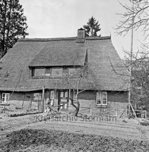 Haus mit Reetdach: ehemalige Voßsche Räucherkate: davor Garten: rechts und links Bäume