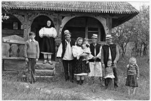 Familie in Trachten vor einem Holzhaus