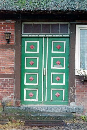 Dorfstraße 10: Schullandheim: traufständiges Fachwerkhaus mit Reetdach: Traufseite, Detailaufnahme: Eingang Flügeltür mit Kassetten und Oberlicht