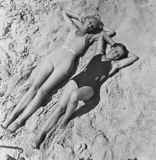 Zwei Frauen in Bademode liegen am Strand