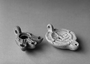 Zwei Öllampen, links Firmallampe (Inv.-Nr. 2055, 1./4. Jh.), rechts Bildlampe mit Reliefdarstellung