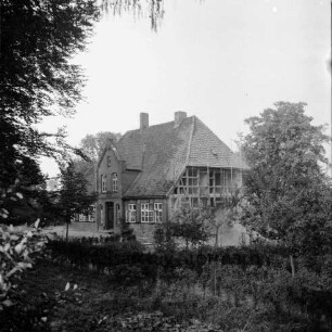 Pastorat: Matthias-Claudius-Straße: Matthias-Claudius-Geburtsstätte [Nachfolgebau von Geburtshaus des Dichters Matthias Claudius]: Restaurierung: Außenansicht: südliche Giebelwand mit Gerüst: gemauerte Gefache entfernt, Fachwerk bleibt stehen: im Vordergrund Garten, Bäume