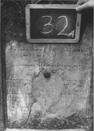 Grabstein 32 (Index: 100112294) Material: Sandstein Zustand: beschädigt und verwittert Maße HxBxT: 165x50x12 cm Beschreibung: Stele, getreppter Sockel, eingezogener Rundbogenabschluß mit Akroteren, Schriftfeld eingetieft mit Rundbogenabschluß Symbolik: Maßwerk: Grabstein 32A