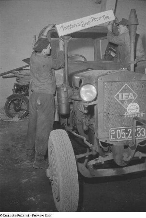 Traktoristen bringen ein Propaganda-Schild über dem Fahrerhaus eines Traktors an