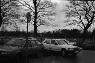 Parkplatz: Pkw beim Rangieren, Autos, Verkehrsschild: hinten Sportplatz