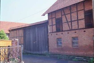 Straßenabschnitt mit Stall und Hoftor eines Gehöftes