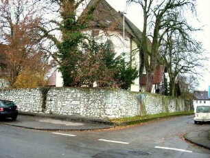 Ansicht von Ostnordosten mit Kirche (Langhaus im Kern Gotisch) über Kirchhofmauer (Wehrgang mit Steinbrüstung im 18 Jh abgetragen)