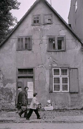 Eine junge Familie vor desolatem Haus im Zentrum von Greifswald ca. 1980