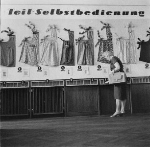 Dresden-Altstadt, Ernst-Thälmann-Straße 25. HO-Warenhaus "Howa". Textilwarenabteilung. Kundin vor einer Musterauslage mit Teil-Selbstbedienung