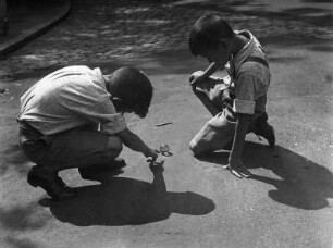 Kinderbilder. Zwei kleine Jungen beim Murmelspielen