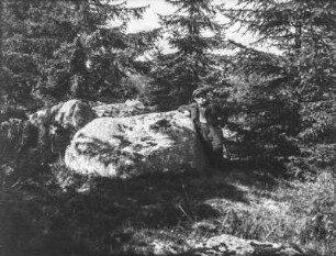 Mann am Felsen : Ein Mann steht an einem Findling im Wald