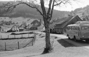 Äule: Postbus mit Ort auf Straße und Berge