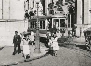 Lissabon. Portugal. Straßenszene. Portugieserinnen tragen ihre Lasten traditionell auf dem Kopf. Im Hintergrund eine Straßenbahn