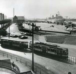 Blick auf die Landungsbrücken : Hamburg-St. Pauli. Blick auf die Landungsbrücken. Ein Passagierschiff liegt an der Überseebrücke. Im Vordergrund eine Straßenbahn der Linie 12