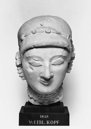 Weiblicher Kopf (Vorderteil) mit haubenartiger Kopfbedeckung, Halsketten und Ohrschmuck