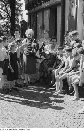 Jungengruppe vor einer Jugendherberge beim Musizieren