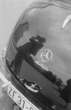 Roger Rössing spiegelt sich beim fotografieren im Heck eines Mercedes
