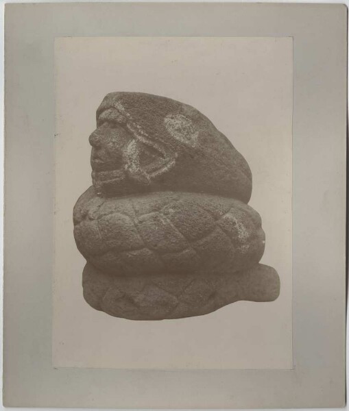 Stone figure. Snake with a human head in its mouth.