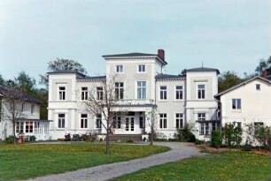 Gut Wulksfelde: ehemaliges Herrenhaus: Straßenfront mit Mittelrisalit, Freitreppe, Vorbau mit eingezogenem Eingangsportal, darüber Altan, zwei Eckrisaliten: beiderseits Kavalierhäuser mit verglasten Eingangsveranden: vorne Vorplatz, junge Bäume, Auffahrt: 9. Mai 2003
