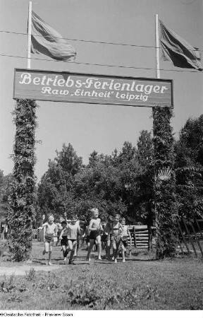 Kinder laufen durch das Eingangstor des Zeltlagers