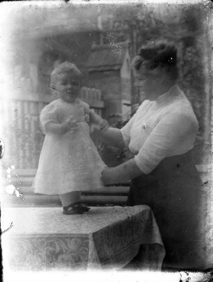 Kattowitz, Friedensstraße 2. Wohnhaus der Familie Knochenhauer. Garten. Fanny Knochenhauer mit einem Jungen (im Taufkleid?) an einem Tisch