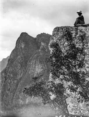 Usambara-Berge : Westhang der westlichen Usambara-Berge. Auf einem Felsen sitzt ein Mitglied der Expedition in Tropenkleidung.
