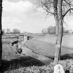 Alster: vorn rechts an Böschung Baum: rechts und links angrenzende Felder: hinten Mitte Sandfelder Schleuse, dahinter Bäume