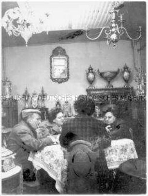 Drei ältere Frauen und ein Mann an einem Tisch, sie spielen